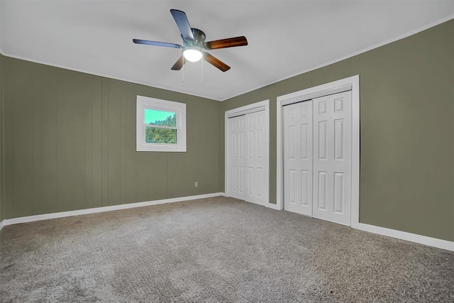 unfurnished bedroom with multiple closets, ceiling fan, and carpet