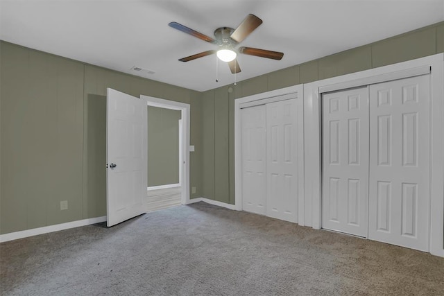 unfurnished bedroom featuring multiple closets, ceiling fan, and carpet floors