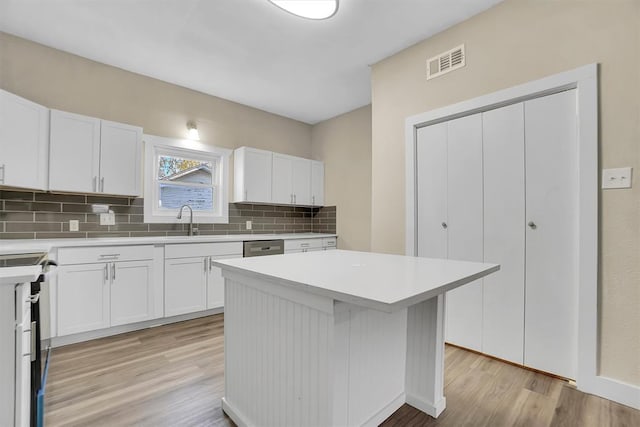 kitchen with white cabinets, a kitchen island, light hardwood / wood-style floors, and sink