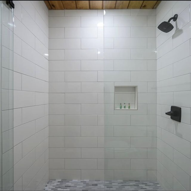 bathroom featuring a tile shower and wooden ceiling