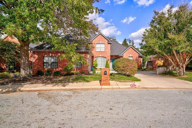 traditional-style home with brick siding, concrete driveway, and a shingled roof