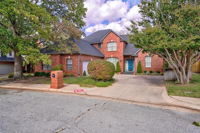 traditional-style home with brick siding, driveway, a shingled roof, and a garage