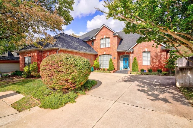 traditional-style home with brick siding, concrete driveway, and a shingled roof