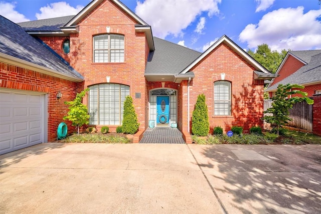 traditional-style home with brick siding, a garage, concrete driveway, and roof with shingles