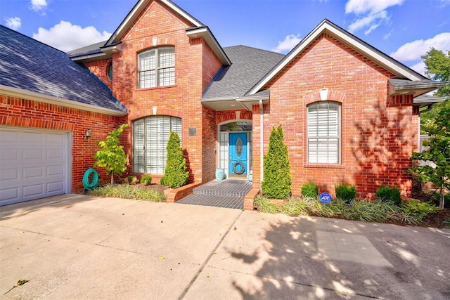 traditional-style house featuring brick siding, driveway, and a shingled roof