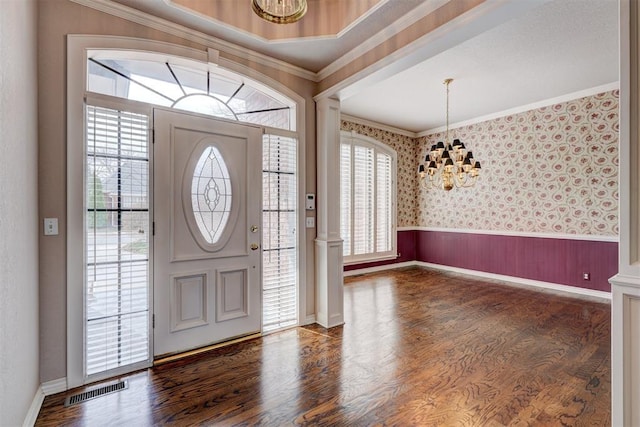 entryway featuring visible vents, a wainscoted wall, wallpapered walls, ornamental molding, and a notable chandelier