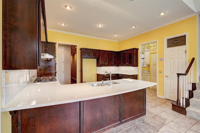 kitchen with a sink, a peninsula, stainless steel gas stovetop, and ornamental molding