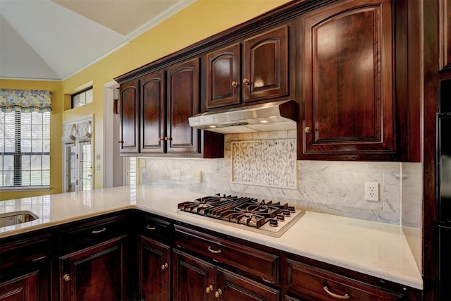 kitchen featuring under cabinet range hood, backsplash, stainless steel gas stovetop, and light countertops