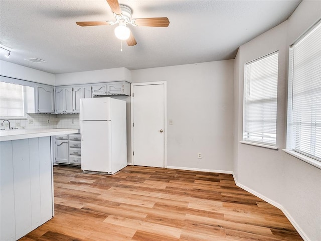 kitchen featuring gray cabinetry, white fridge, light hardwood / wood-style floors, and a wealth of natural light