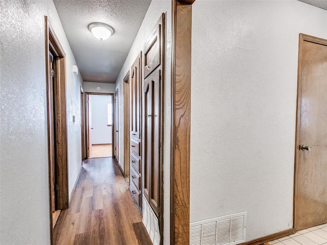 hall featuring light hardwood / wood-style floors and a textured ceiling