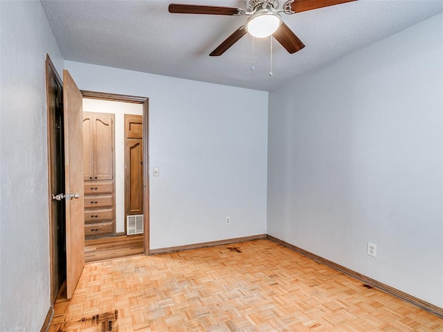 empty room with ceiling fan, light parquet floors, and a textured ceiling