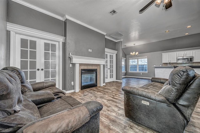 living room featuring lofted ceiling, french doors, crown molding, hardwood / wood-style flooring, and a tiled fireplace