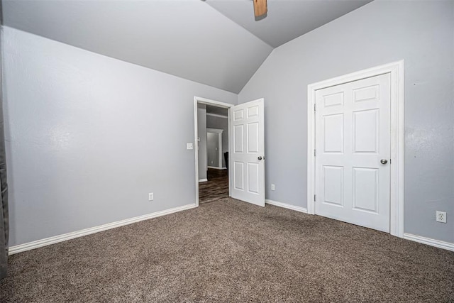 unfurnished bedroom featuring ceiling fan, vaulted ceiling, and dark colored carpet