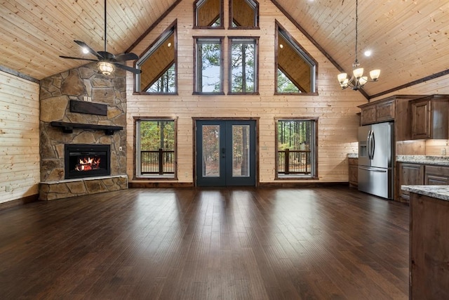 unfurnished living room with wood ceiling, high vaulted ceiling, dark hardwood / wood-style floors, a stone fireplace, and wood walls