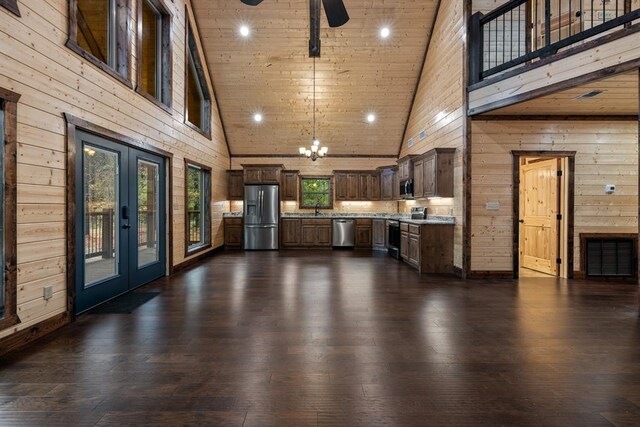 unfurnished living room with dark hardwood / wood-style floors, wood walls, high vaulted ceiling, and french doors