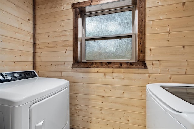 laundry room with wooden walls and washing machine and clothes dryer