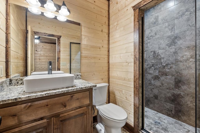 bathroom featuring an enclosed shower, vanity, wood walls, and toilet