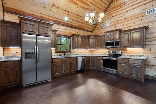 kitchen featuring dark wood-type flooring, sink, decorative light fixtures, light stone counters, and stainless steel appliances