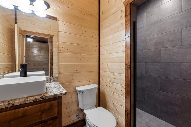 bathroom featuring vanity, toilet, and wooden walls