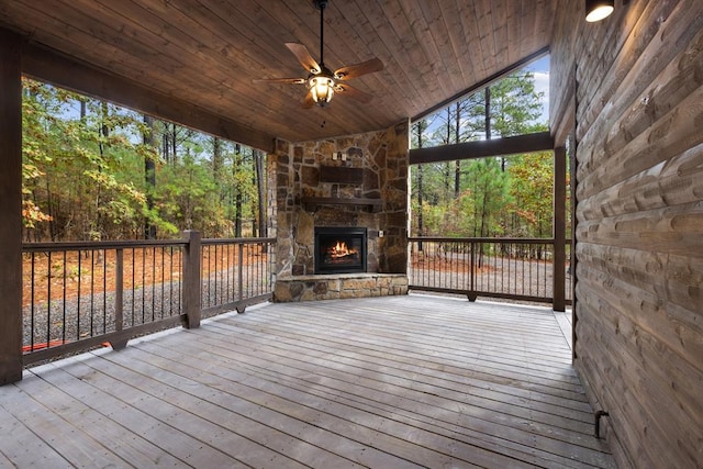 wooden deck with an outdoor stone fireplace and ceiling fan