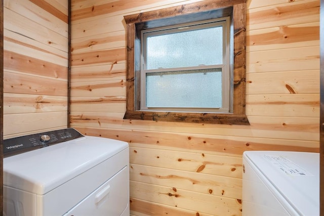 clothes washing area with washer / clothes dryer and wood walls