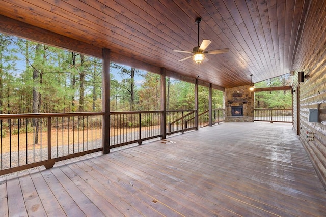 wooden deck featuring an outdoor stone fireplace and ceiling fan