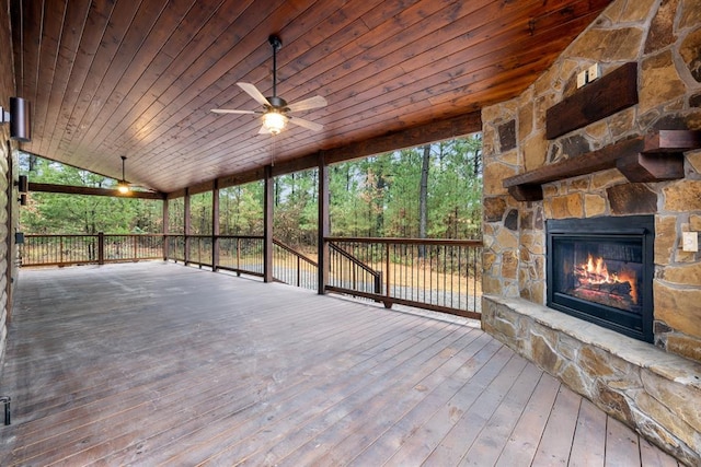 deck with an outdoor stone fireplace and ceiling fan