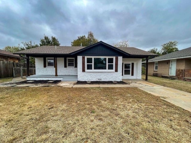 ranch-style home featuring covered porch and a front yard