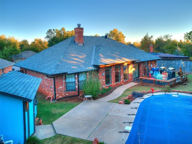 rear view of house featuring a covered pool, a yard, and a patio area