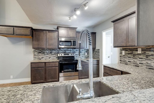 kitchen featuring backsplash, light stone counters, dark brown cabinetry, and stainless steel appliances