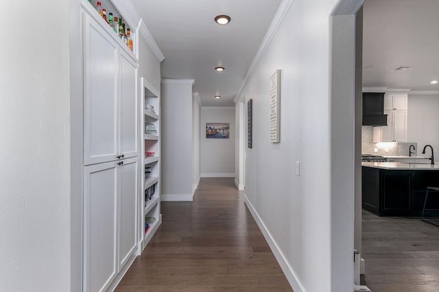 corridor with crown molding, dark hardwood / wood-style flooring, and sink