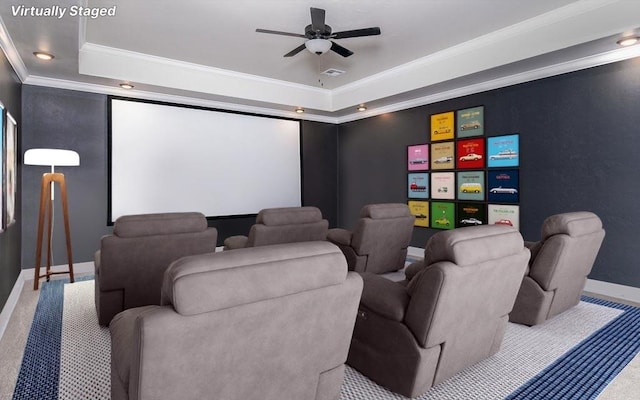 cinema room with carpet, a raised ceiling, ceiling fan, and ornamental molding