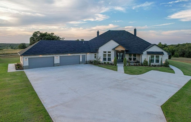 view of front of property with a garage and a lawn