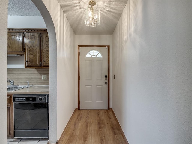 entryway featuring a textured ceiling, light hardwood / wood-style floors, a notable chandelier, and sink