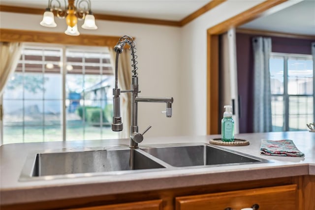 kitchen featuring pendant lighting, an inviting chandelier, crown molding, and sink