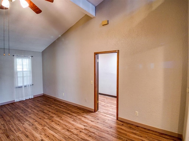 empty room with hardwood / wood-style flooring, vaulted ceiling with beams, and ceiling fan