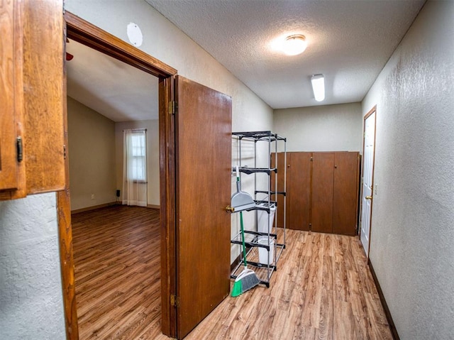 hall with light hardwood / wood-style floors and a textured ceiling