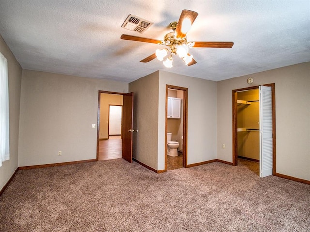 unfurnished bedroom featuring connected bathroom, ceiling fan, carpet, and a textured ceiling