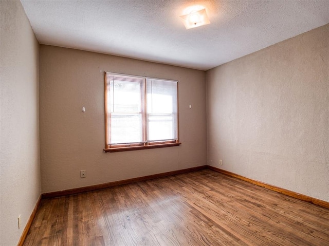 empty room with hardwood / wood-style flooring and a textured ceiling