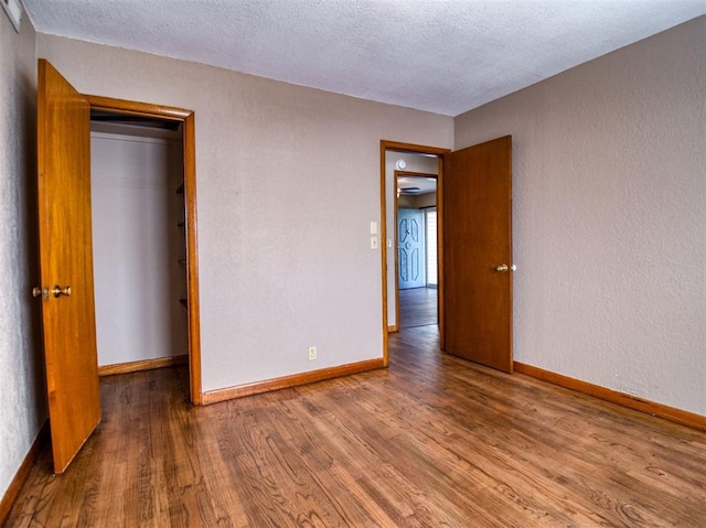 unfurnished bedroom featuring a closet, hardwood / wood-style floors, and a textured ceiling