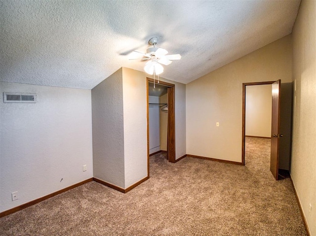 interior space featuring a textured ceiling, light colored carpet, ceiling fan, and lofted ceiling