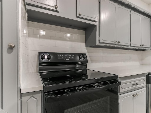 kitchen featuring tasteful backsplash, white cabinetry, and black / electric stove