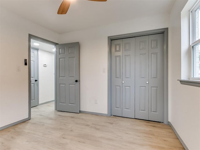 unfurnished bedroom with light hardwood / wood-style flooring, a closet, and ceiling fan