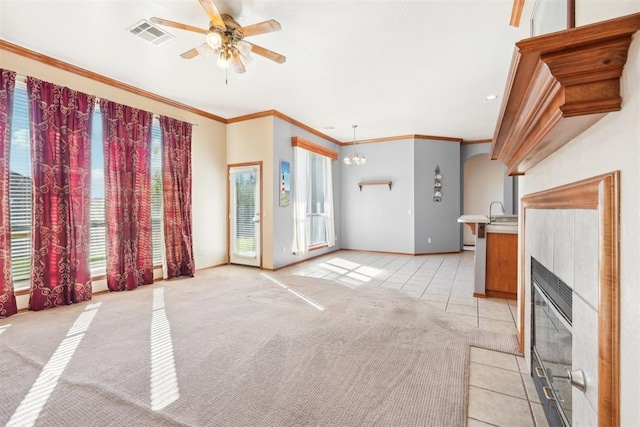 unfurnished living room featuring light tile patterned floors, a healthy amount of sunlight, ceiling fan with notable chandelier, and ornamental molding