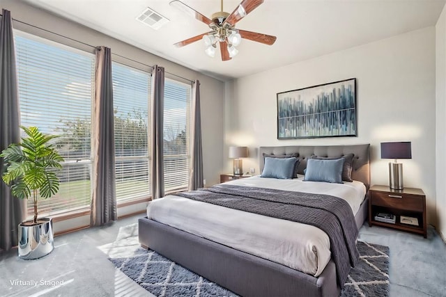 carpeted bedroom featuring multiple windows and ceiling fan