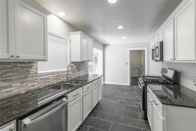 kitchen featuring dark stone countertops, sink, white cabinets, and stainless steel appliances