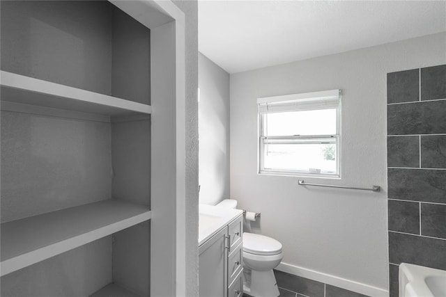 bathroom featuring tile patterned flooring, vanity, a bath, and toilet