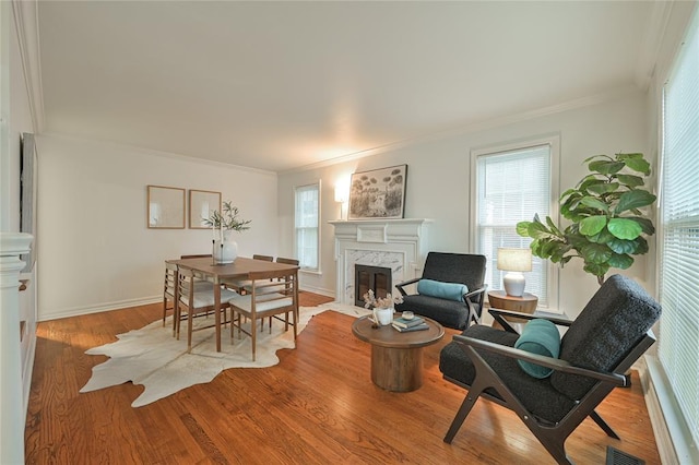 dining area featuring light wood-type flooring, crown molding, and a premium fireplace