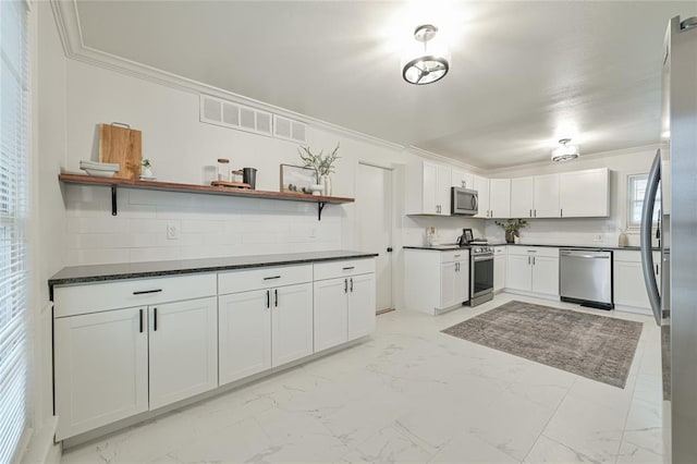 kitchen featuring tasteful backsplash, white cabinetry, stainless steel appliances, and ornamental molding