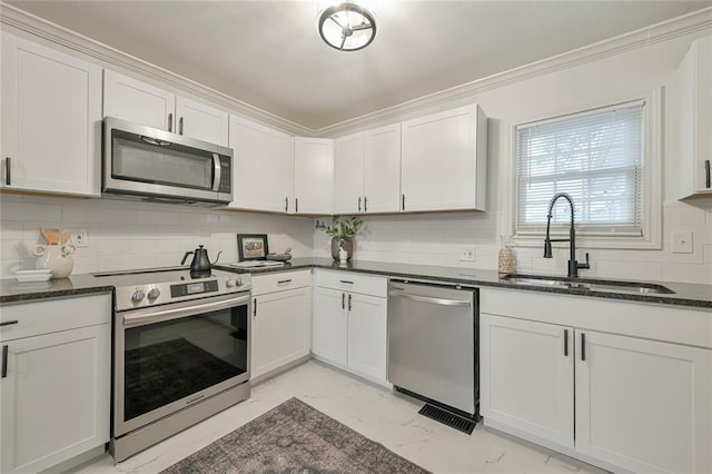 kitchen featuring appliances with stainless steel finishes, tasteful backsplash, sink, dark stone countertops, and white cabinetry